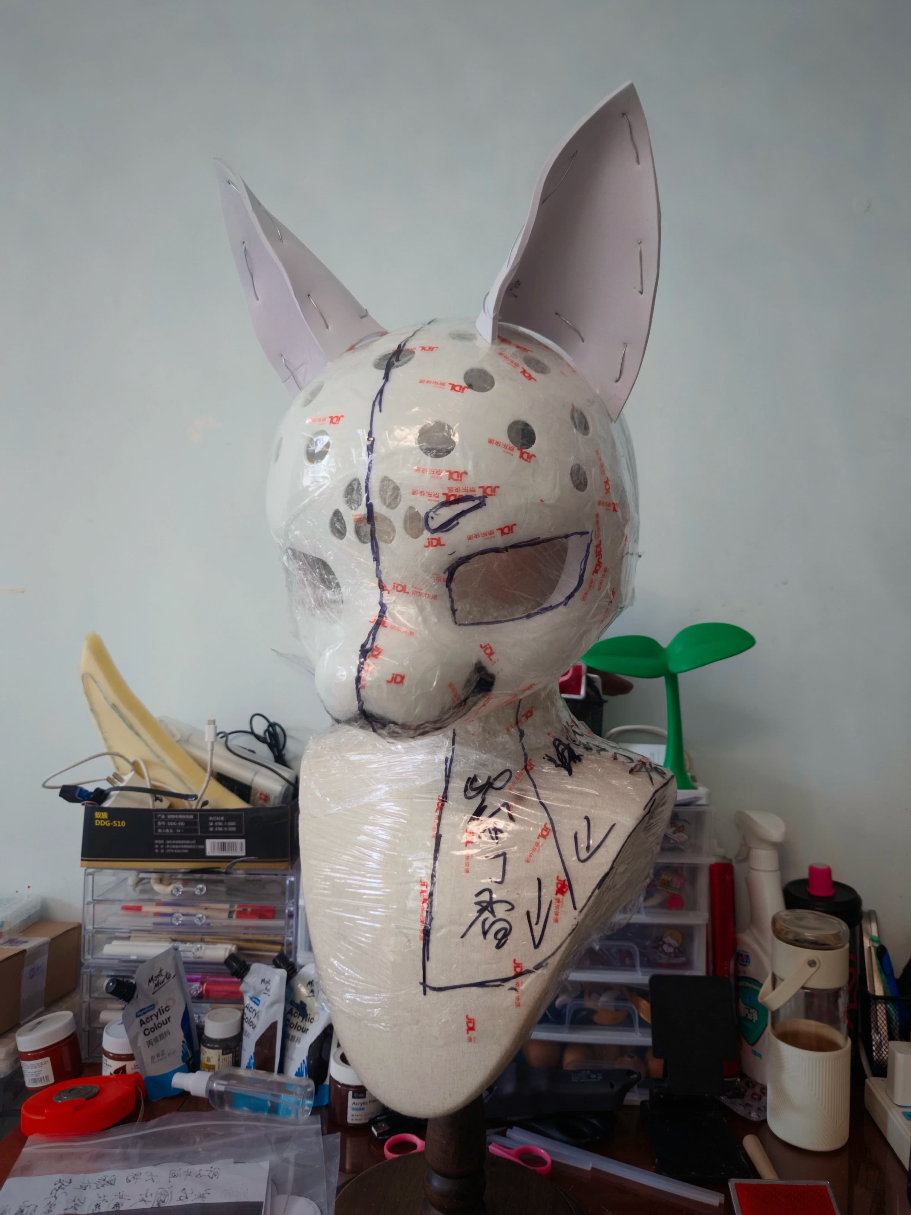 Behind the scenes fursuit head base in progress, foam and tape construction with pattern markings in artist's workshop